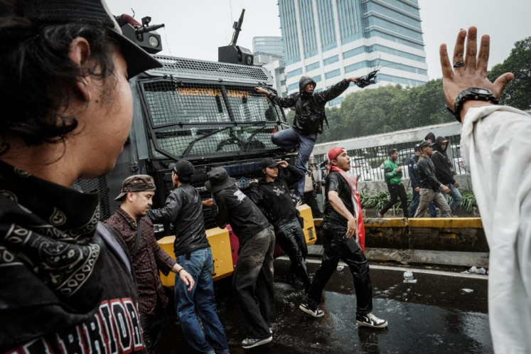 Protesters try to block a police water cannon vehicle during their demonstration protesting lawmakers' pay in front of the House of Representatives building in Jakarta on August 25, 2025.