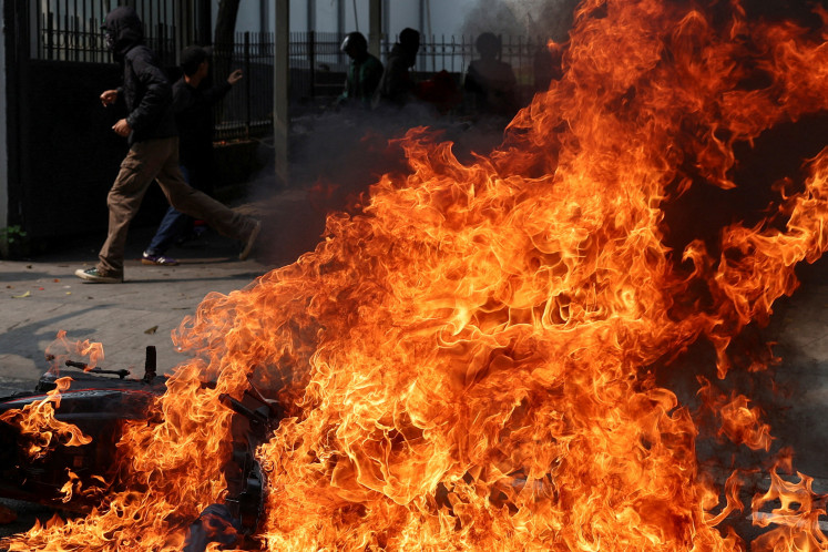 A man runs past a fire outside the Senayan legislative complex in Jakarta on Aug. 25, 2025, after protesters clashed with police over what they said were exorbitant allowances for lawmakers.