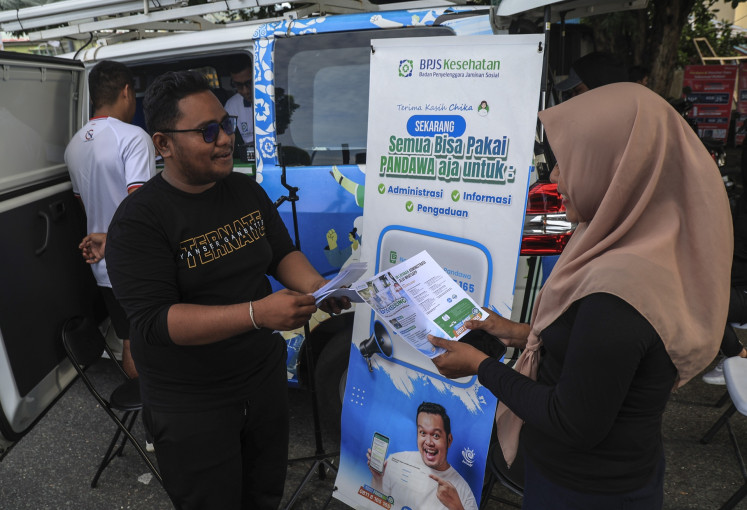 A Health Care and Social Security Agency (BPJS Kesehatan) official provides information about the National Health Insurance (JKN) to passers-by during a car-free day event in Ternate, North Maluku, on Aug. 10, 2025.