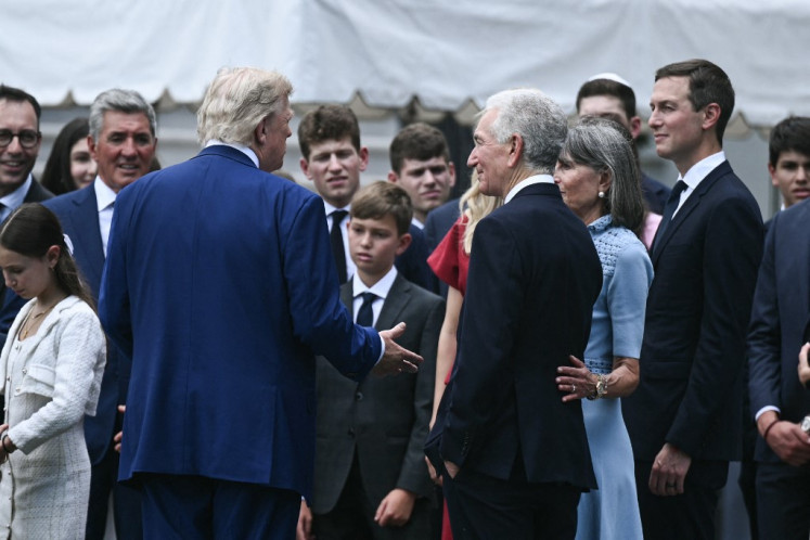 US President Donald Trump speaks with a group of people, including newly sworn in Ambassador to France Charles Kushner (3rd right) and Jared Kushner (right), as a US flag is raised on a newly installed flagpole on the South Lawn of the White House in Washington, DC on June 18, 2025. 