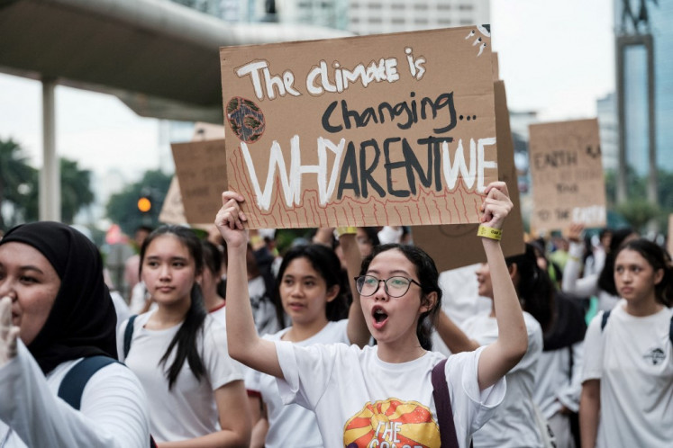 Participants hold placards on April 21, 2024, as they march on a street ahead of Earth Day on April 22, annual environmental awareness day, in Jakarta.