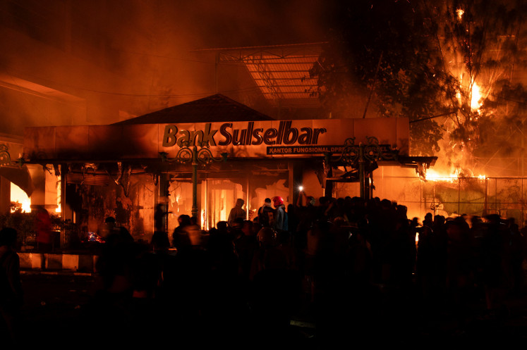 Protesters gather near the burning Makassar City Council building in Makassar, South Sulawesi on Aug. 30, 2025 during a protest after a motorcycle taxi driver died after being struck and run over by a police tactical vehicle during another protest against lavish allowances for House of Representatives lawmakers.