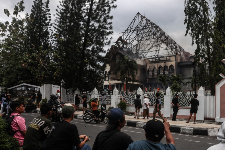 People look at the the West Nusa Tenggara (NTB) Representatives Council (DPRD) office building, seen partially burned after being stormed, looted and set on fire during a demonstration in Mataram, NTB on Aug. 30, 2025. Protests rock Indonesian major cities including Jakarta on Aug. 29 after footage spread of a ride-hailing driver being run over by a police tactical vehicle in earlier rallies against low wages and financial perks for lawmakers.