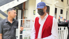 Defendant Roman Nazarenko from Ukraine (center) is being escorted to a detention center after a trial session on Aug. 28 at the Denpasar District Court in Denpasar, Bali. The prosecutors demanded a life sentence against Nazarenko for leading a drug laboratory in Canggu, North Kuta district, Badung regency, Bali.