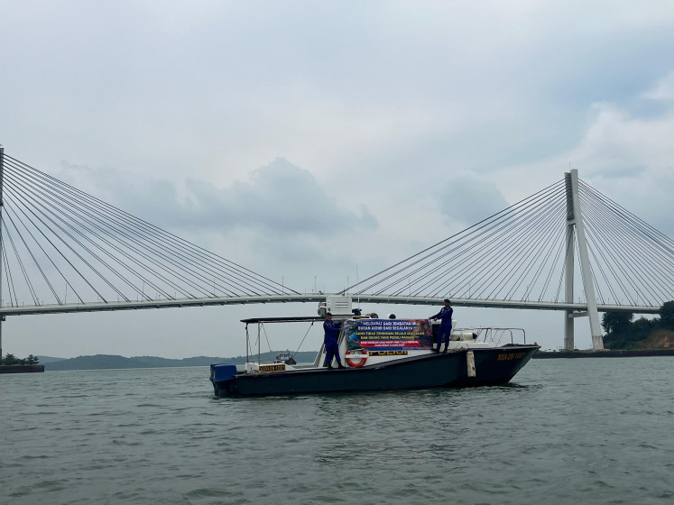 Officers from the Water and Air Police (Polairud) Unit of the Barelang City Police display a suicide prevention banner on Wednesday on a boat near the Tengku Fisabilillah Bridge, more popularly known as Barelang Bridge, in the waters off Batam, Riau Islands. The police are asking the public to be more sensitive to the psychological pressures facing those around them. 