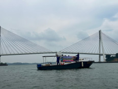 Officers from the Water and Air Police (Polairud) Unit of the Barelang City Police display a banner for suicide prevention on Aug. 27, 2025, on a boat with the Tengku Fisabilillah Bridge, more popularly known as the Barelang Bridge, on the waters off Batam, Riau Islands. The police are asking people to be more sensitive to psychological pressures on people around them. 