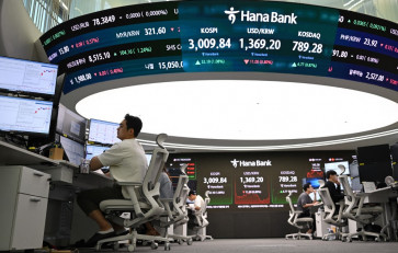 Currency dealers monitor exchange rates beneath a big screen showing South Korea's benchmark stock index (KOSPI) and the Korean won/USD exchange rate in a foreign exchange dealing room at the Hana Bank headquarters in Seoul on June 20, 2025.