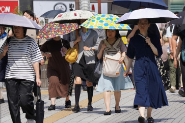 People with umbrellas walk in the scorching sun in Tokyo on September 1, 2025.