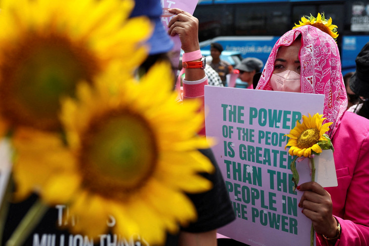 Activists carrying sunflowers hold placards during a protest against lawmakers' perks and police brutality, while some brandish brooms as a symbol of their calls for reform, on Sept. 3 outside the Senayan legislative complex in Jakarta.