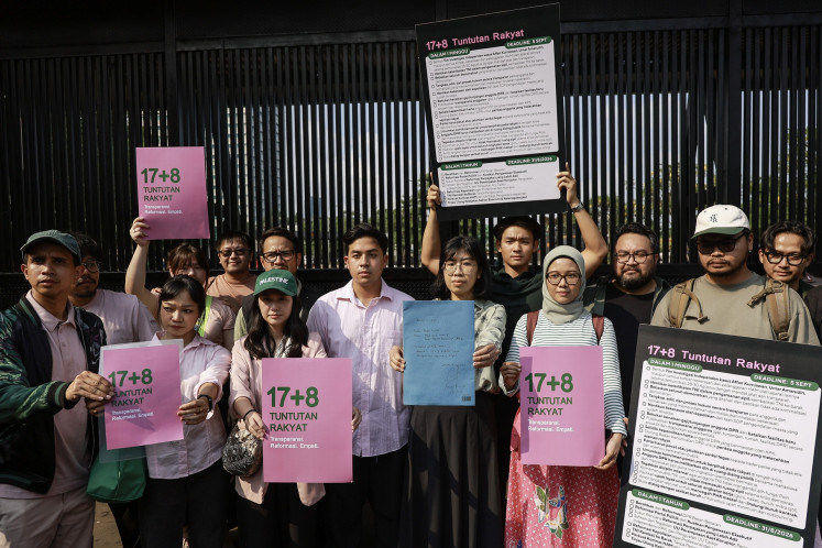 Online influencers and activists from the “17+8 People's Demands“ collective campaign hold posters after giving a document of short- and long-term demands to lawmakers at the Senayan legislative complex in Jakarta on Sept. 4, 2025.