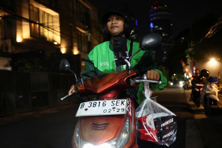 Pratiwi Ariyanti, a 38-year-old ojol (online motorcycle transportation driver), rides her motorcycle in Jakarta on Sept. 3, 2025 after picking up food ordered and donated by a customer from overseas in solidarity with the Indonesian protests.