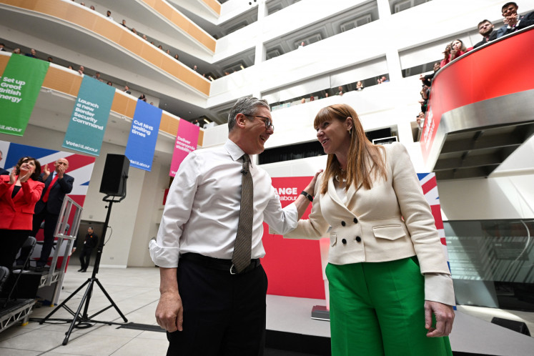 Britain's Labor Party leader Keir Starmer (left) and Britain's Labor Party deputy leader Angela Rayner (right) acknowledge the audience as they arrive for the launching of Labor Party election manifesto, in Manchester, on June 13, 2024 in the build-up to the UK general election on July 4. 