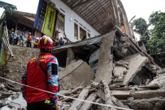 A rescue worker looks at the remains of a community Islamic study hall that collapsed while female Muslims were conducting studies to commemorate the birthday of the Prophet Muhammad in Bogor, West Java, on September 7, 2025. According to the Regional Disaster Management Agency (BPBD), three women were killed and 65 others injured as rescue teams from the agency, police, army and volunteers responded. 