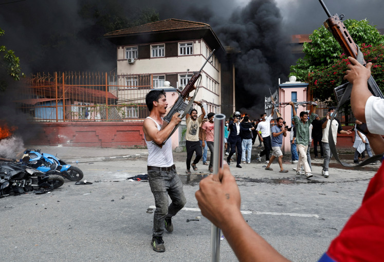 People wielding weapons looted from the Supreme Court take part in a demonstration in front of the top court in Kathmandu on Sept. 9, 2025, to protest the 19 people who were killed the previous day during anticorruption protests, initially triggered by the Nepali government’s ban on social media platforms.