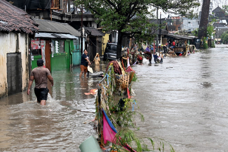Residents wade through floodwaters in their neighborhood following heavy rainfall in Denpasar, Bali, on September 10, 2025. 