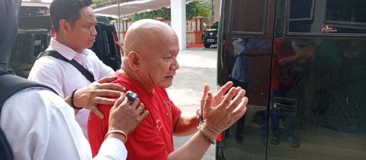 Yusril Koto, 61, a social activist on trial for defamation at the Batam District Court in the Riau Islands, is escorted to a detention car after a hearing on Sept. 9, 2025.