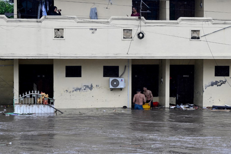 Residents wade through floodwaters in their neighbourhood following heavy rainfall in Denpasar, Bali, on September 10, 2025. 