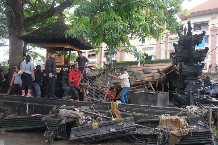 Aftermath: Residents inspect the condition of a temple damaged by flooding on Sept. 11 at Kumbasari Market in Denpasar. The Bali Disaster Management Agency (BPBD) recorded more than 120 areas hit by the flooding in seven regencies and cities in Bali. The disaster left at least 14 people dead and two missing.