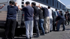 Detainees are made to stand against a bus before being handcuffed, during a raid by federal agents where about 300 South Koreans were among 475 people arrested at the site of a $4.3 billion project by Hyundai Motor and LG Energy Solution to build batteries for electric cars in Ellabell, Georgia, US, on Sept. 4, 2025 in a handout still image taken from a video.