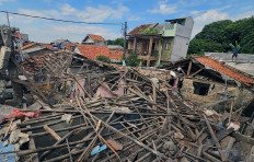 A resident walks across a rooftop near the rubble of houses damaged by an explosion in Pamulang, South Tangerang, Banten, on Sept. 12, 2025. The cause of the blast, which injured seven people, remains under investigation.