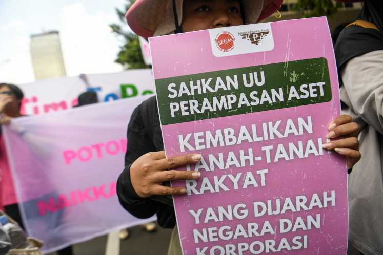 A protester holds a poster that reads “Pass the asset forfeiture bill. Return people's lands taken by the state and corporations“ during a demonstration organized by the labor unions with the People's Movement (Gebrak) in Jakarta on Sept. 4, 2025.