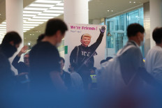 An activist holds a banner as South Korean workers who were detained in a huge immigration raid last week at the site of a United States car battery project involving Hyundai Motor and LG Energy Solution in the country's state of Georgia, arrive at the Incheon International Airport in Incheon, South Korea, on Sept. 12, 2025.