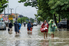 People carrying their belongings wade through a flooded street following overnight heavy rains on Sept. 10 in Legian, Badung, Bali.