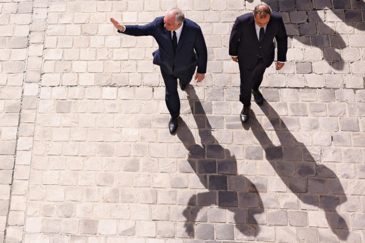 France's outgoing prime minister, Francois Bayrou (left), waves to guests as he is escorted toward the exit by newly-appointed Prime Minister and former Minister of Armed Forces Sebastien Lecornu (right) at the end of the handover ceremony at the Hotel Matignon in Paris on Sept. 10, 2025. / POOL / AFP)