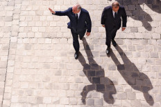 France's outgoing prime minister, Francois Bayrou (left), waves to guests as he is escorted toward the exit by newly-appointed Prime Minister and former Minister of Armed Forces Sebastien Lecornu (right) at the end of the handover ceremony at the Hotel Matignon in Paris on Sept. 10, 2025. / POOL / AFP)