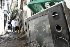 President Prabowo Subianto (right) and Cabinet Secretary Teddy Indra Wijaya walk through narrow alleys on Sept. 13 in the Gerenceng area in Denpasar, Bali, to meet residents affected by severe floods.
