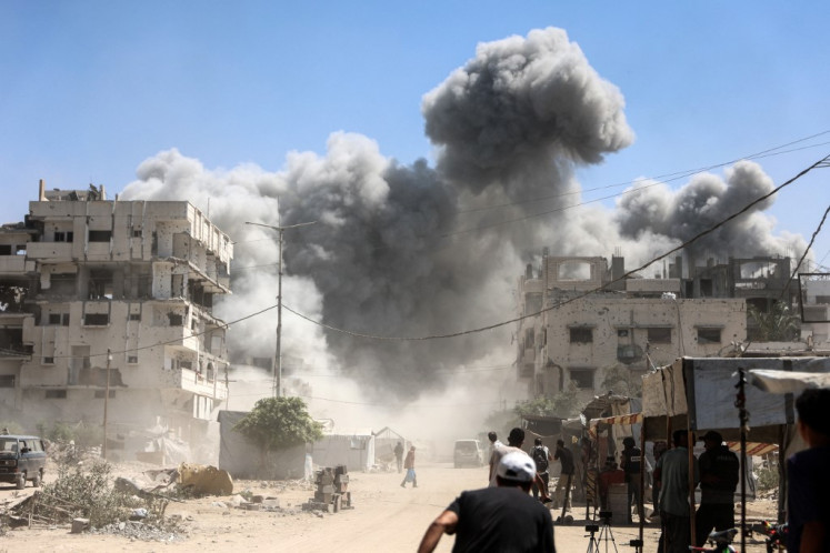 Palestinians watch as the Mhanna tower collapses amid heavy smoke, during an Israeli strike in the Tal el-Hawa neighbourhood of Gaza City on September 14, 2025. 