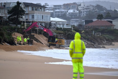 A file photo taken on July 2, 2025 shows workers operating heavy machinery to stabilize Wamberal Beach as a low-pressure cyclone lashes the Central Coast, forcing residents to evacuate beachfront homes amid growing erosion fears. 