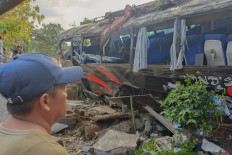 A man observes the wreckage of a tour bus that crashed in Lumbang, East Java, on Sept. 14, 2025. The accident, reportedly caused by brake failure, left eight passengers dead.