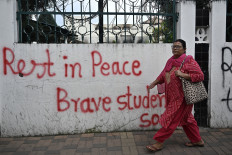 A woman walks past a graffitied wall outside the torched Parliament building on Sunday in Kathmandu. Nepal's new leader Sushila Karki vowed on Sunday to meet protesters' demands to “end corruption“ as she began work as interim prime minister, after youth demonstrations ousted her predecessor.
