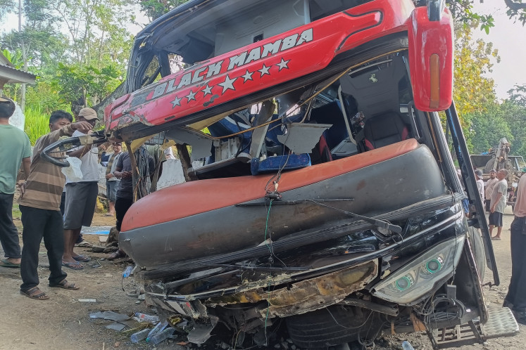 A crowd gathers on Sept. 14, 2025, to look at the remains of a bus in Lumbang district, Probolinggo regency, East Java. The bus was carrying 52 employees of Bina Sehat Jember Hospital and their families when it veered off Jl. Raya Bromo and struck a guardrail, killing eight and injuring at least 15 people.