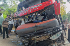 A crowd gathers on Sept. 14, 2025, to look at the remains of a bus in Lumbang district, Probolinggo regency, East Java. The bus was carrying 52 employees of Bina Sehat Jember Hospital and their families when it veered off Jl. Raya Bromo and struck a guardrail, killing eight and injuring at least 15 people.