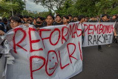 Fed up: Civil society activists and university students hold a banner that reads “Police reform“ (left) and “People's killer“ on Nov. 28, 2024, during a protest in front of the Central Java Police station in Semarang. 