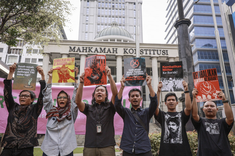 Activists of Civil Society Coalition for Security Sector Reform hold posters on Wednesday during a demonstration in front of the Constitutional Court building in Jakarta. They urged court justices to rule in their favor in a judicial review case against the recently passed Indonesian Military (TNI) Law revision.