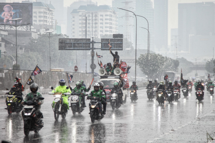 Ojol (online motorcycle transportation drivers) protest in the rain at the main entrance of the House of Representatives complex in Central Jakarta on Sept. 17, 2025. They demanded better welfare protection and a full investigation into the death of an Ojol during an August rally.