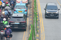 An electric car of Chinese carmaker BYD (right) drives past bumper-to-bumper traffic in an opposing lane on Sept. 19, 2025, during rush hour in Jakarta.