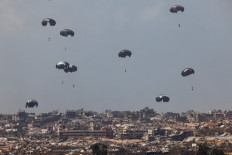 Fraternal help: Humanitarian aid packages, dropped from an Indonesian Air Force Hercules aircraft, descend on Aug. 21 over the Gaza Strip, Palestine, as seen from Israel.