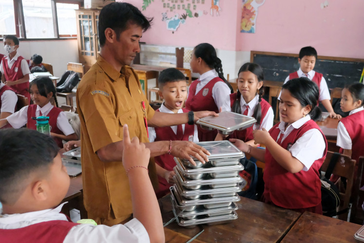 A teacher distributes free meals on Sept. 8, 2025, at SDN 3 Delod Peken state elementary school in Tabanan, Bali.