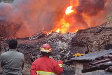 Two men look at a fire burning at an unregulated oil well on Sept. 12, 2025, in Gandu village, Bogorejo district, Blora regency, Central Java.