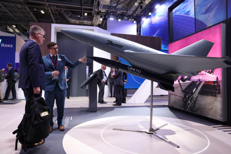 Delegates talk on Sept. 9 at the stand of British defense contractors QinetiQ next to a Banshee target drone UAV at Swedish company Mildef's stand at the Defence and Security Equipment International (DSEI) fair at the ExCeL centre, in east London.