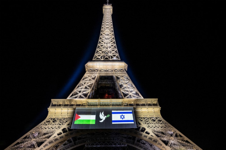 This photograph shows images of Palestinian (left) and Israeli (right) flags and a dove with an olive branch, projected onto the Eiffel Tower on the eve of France's planned recognition of the State of Palestine, in Paris, on September 21, 2025.