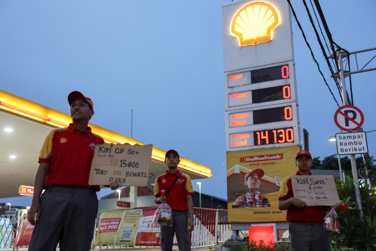 Employees selling snacks, coffee and oil in front of a Shell gas station in Jakarta wait for customers on Sept. 19, 2025.