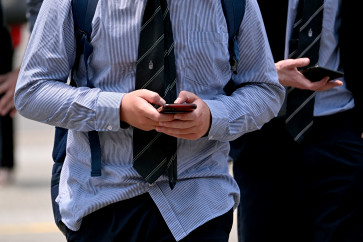 A file photo taken on November 28, 2024 shows people looking at their phones in Melbourne, Australia. 