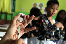 A medical staff member prepares a shot for a student of state elementary school SDN Tanjungrejo 5 on Nov. 5 in Malang, East Java, during a free health checkup (CKG) event in the School Children Immunization Month (BIAS) mass vaccination campaign. 