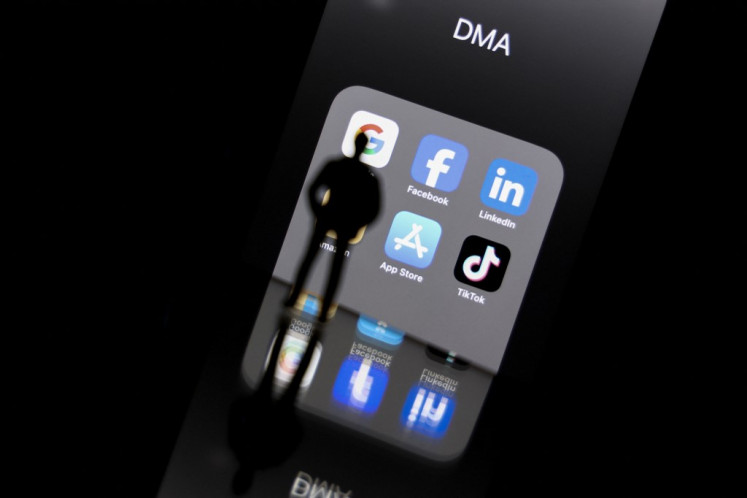 This photo taken on Feb. 12, 2023, in Brussels shows reflections on a smartphone screen of logos of online platforms Google, Facebook, LinkedIn, Amazon, Apple store and TikTok as the European Commission announced the world's biggest digital firms, identified as “gatekeepers“ by the EU, must comply with strict do's and don'ts under the Digital Markets Act (DMA).