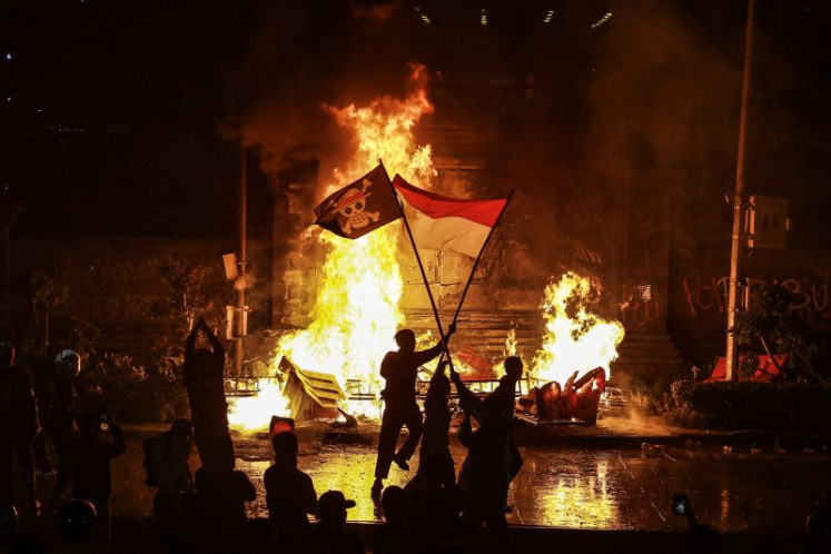 Protestors wave the Red and White flag and the Straw Hat Pirates flag from Japanese manga ‘One Piece’ on Aug. 29, 2025, during a rally outside the Jakarta Metropolitan Police headquarters on Jl. Sudirman.